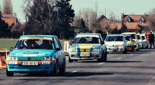 Des voitures de course (lors d'un rallye) en file indienne sur une route