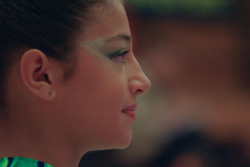 Le visage d'une fille en gros plan, de profil. Elle a les yeux légèrement maquillés en vert. Elle regarde vers la droite et semble concentrée.