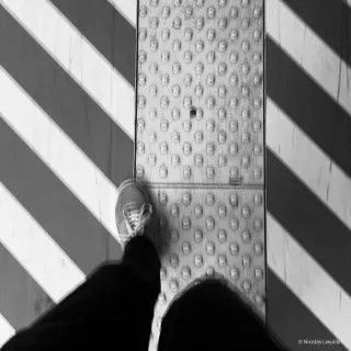 Photo en noir et blanc des pieds du photographe. Il y a un effet de mouvement sur cette photo.