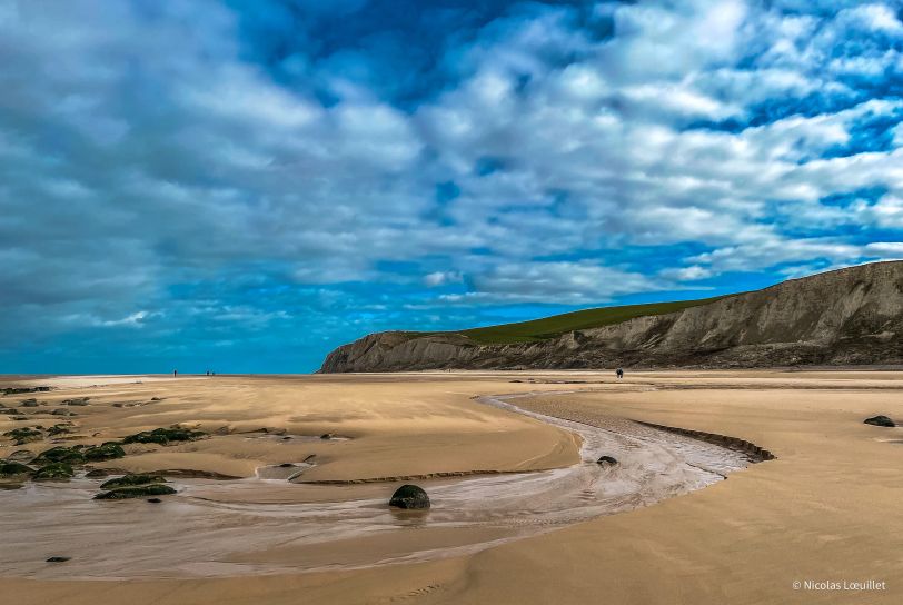 Photo aux couleurs vives d'une plage. En arrière-plan, le Cap Blanc-Nez.