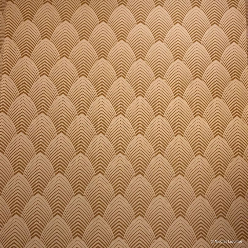 Des formes géométriques (sorte d'ogive) tapissent un mur.